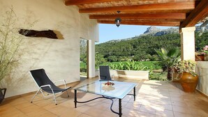 An outdoor patio with a glass table and two chairs, a wooden ceiling, and a view of a mountainous landscape. - PLANA. Fantastic villa in a very quiet area (Pollensa)