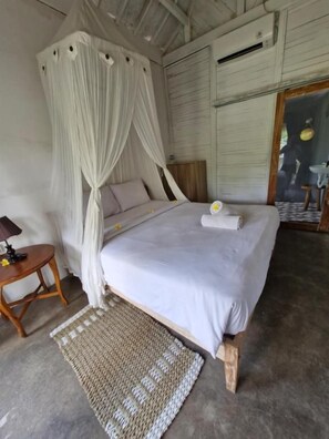 A bedroom with a bed, a bedside table, a rug, and a canopy. - The Layar Homestay (Penida Island)