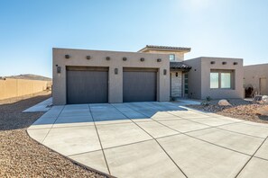 A modern house with two garage doors, a patio, and a small garden area.