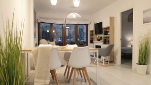 A modern dining area with a wooden table, white chairs, and hanging pendant lights.