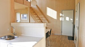 Un intérieur en bois comprenant un espace cuisine, un escalier et une porte.