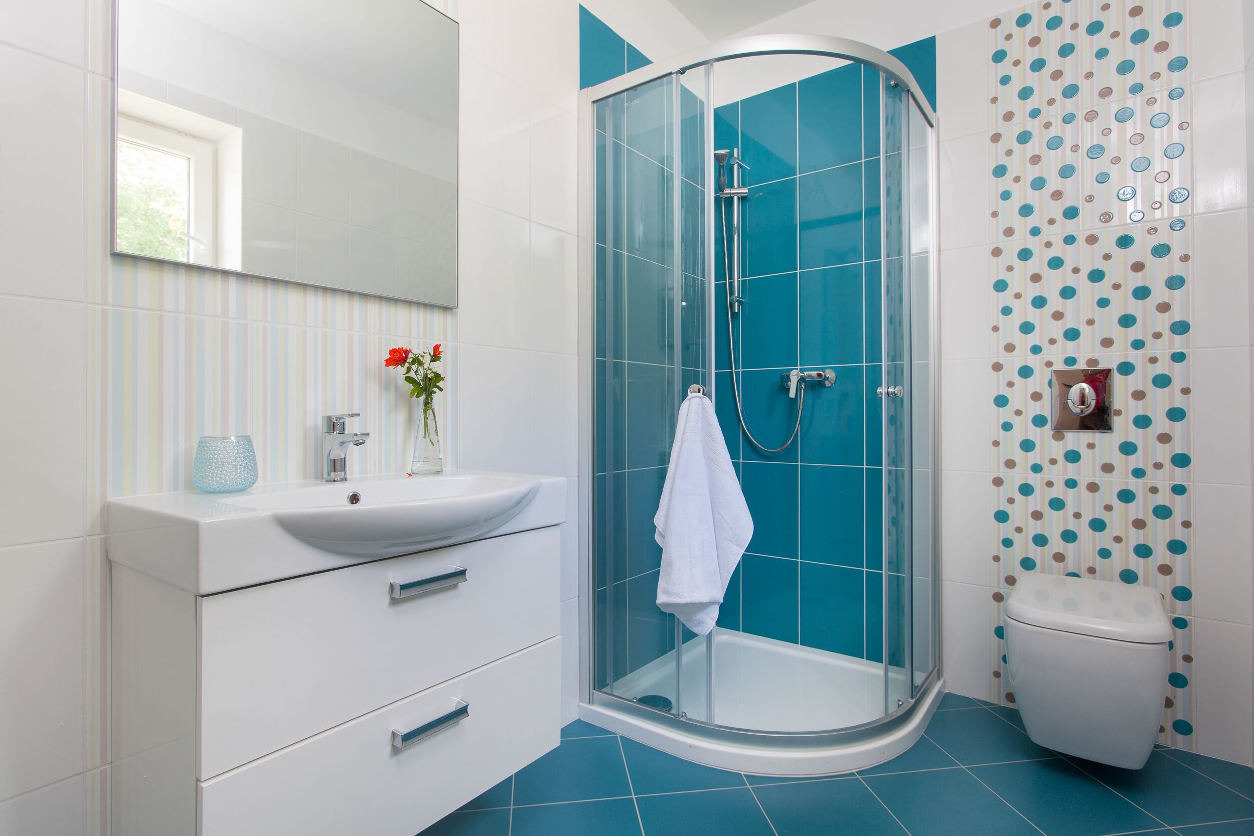A modern bathroom with a glass-enclosed shower, white vanity, and a toilet.