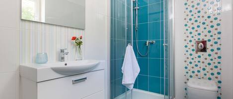 A modern bathroom with a glass-enclosed shower, white vanity, and a toilet.