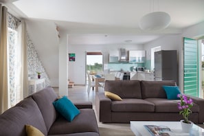 A modern living room with two sofas, a coffee table, and a view into the kitchen.