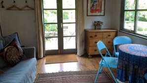 A room with a sofa, a table with a patterned tablecloth, a dresser, and a painting on the wall.
