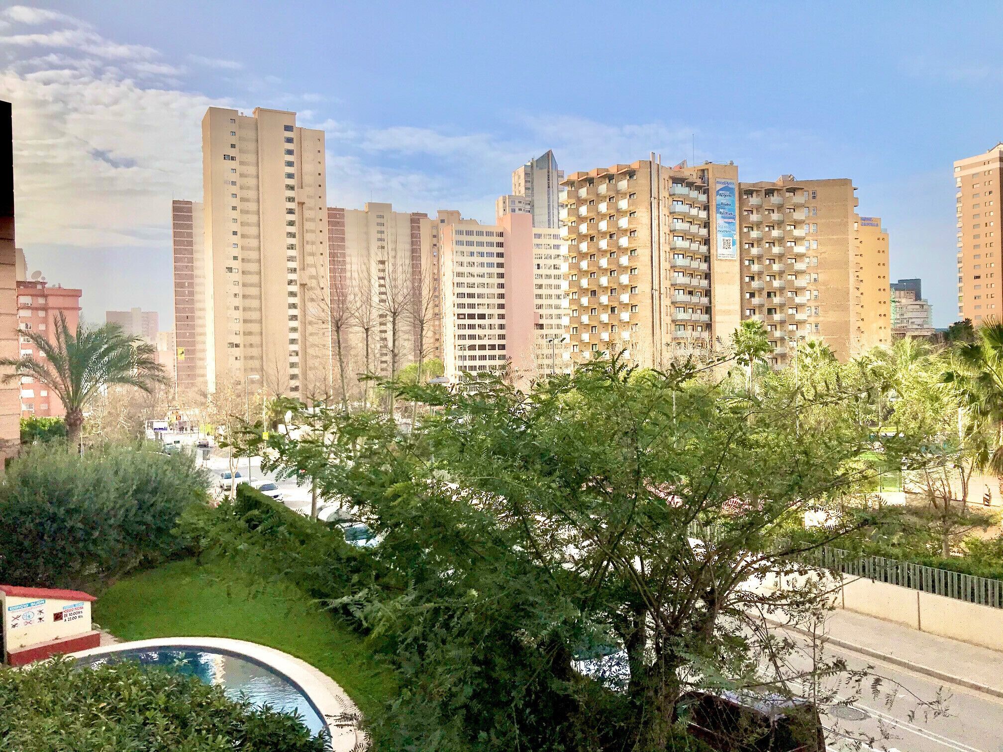 A residential area with high-rise buildings, a swimming pool, and greenery.