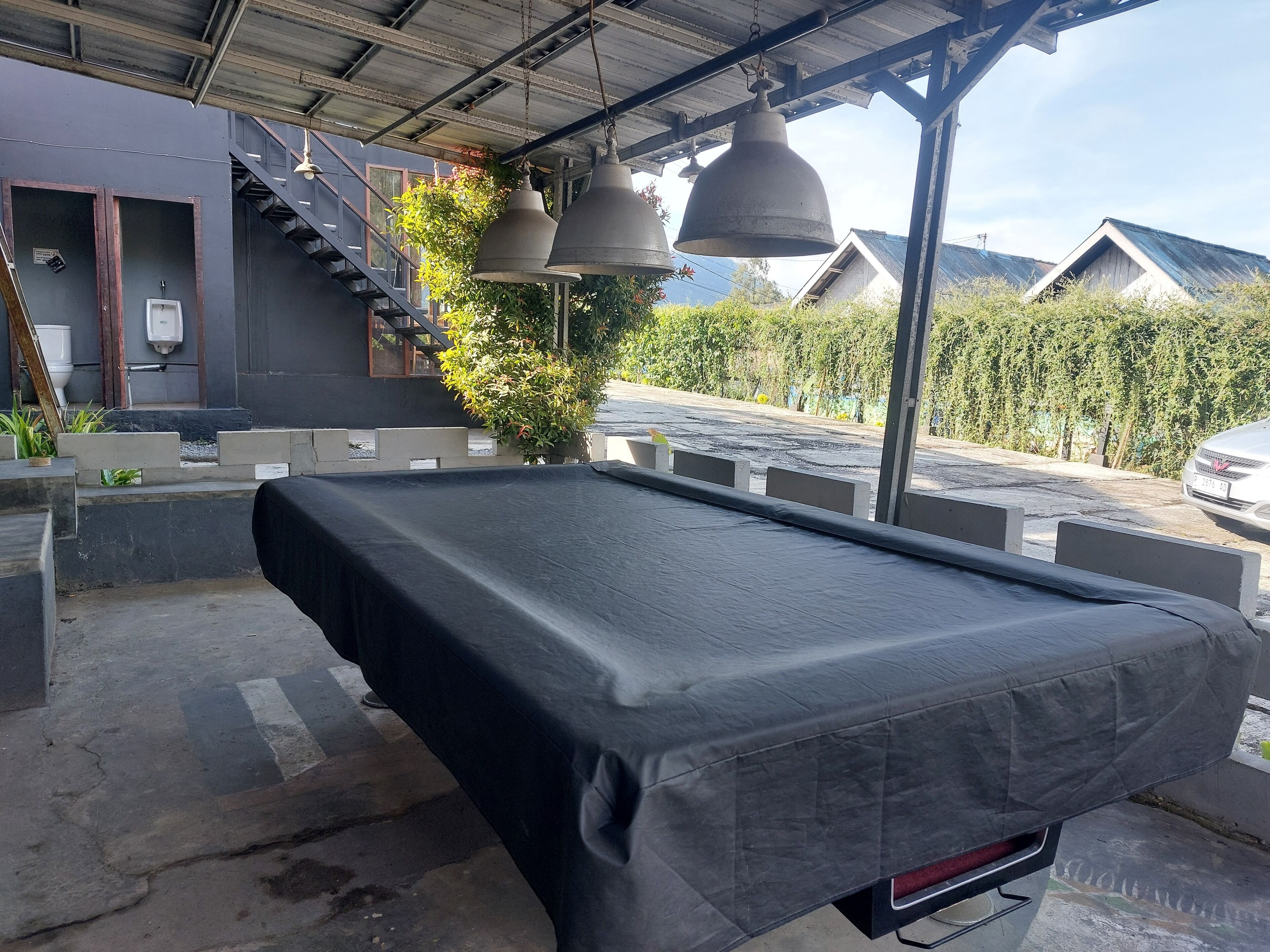 A covered outdoor area with a pool table, a staircase, and hanging bells.
