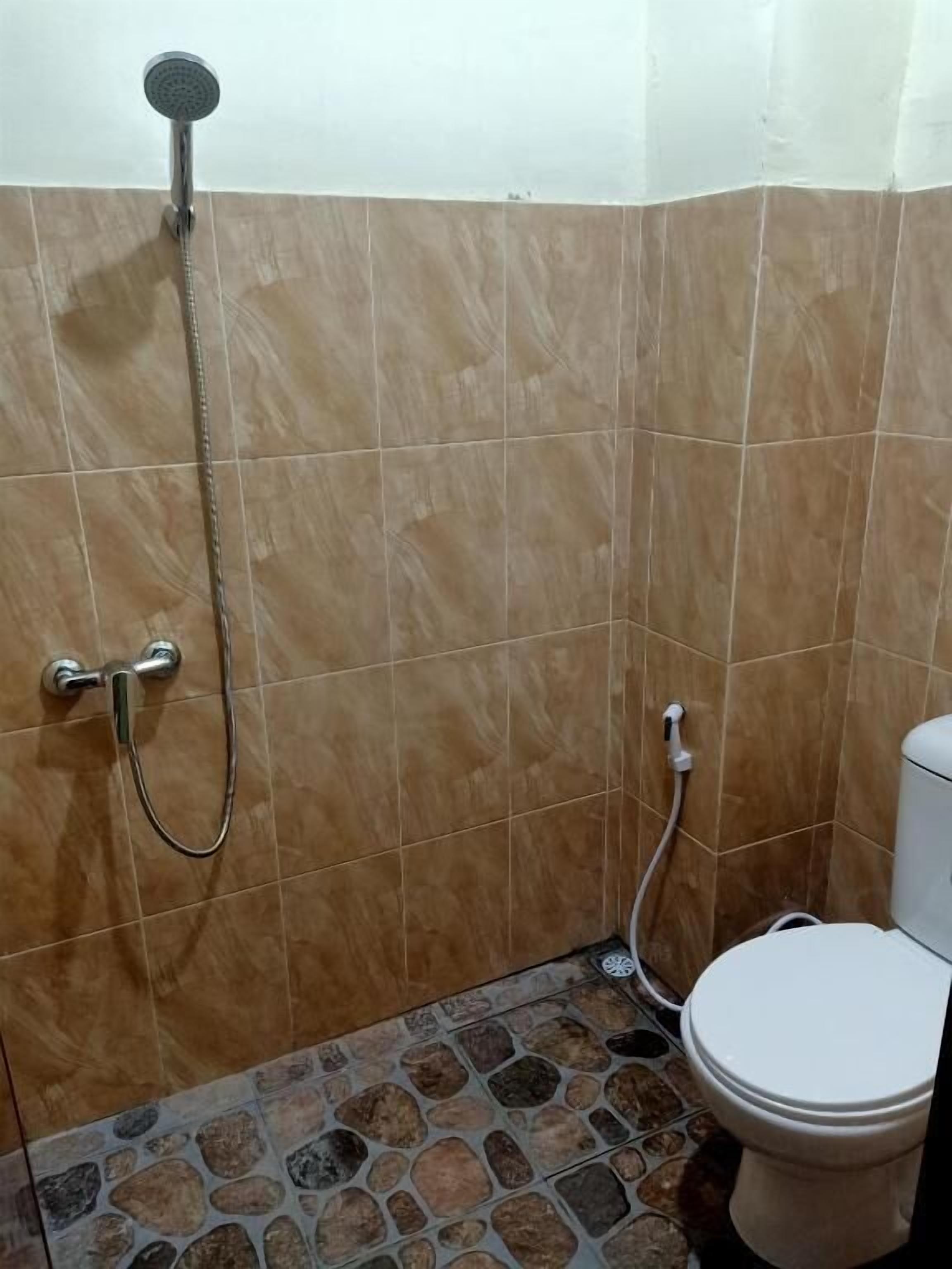 A bathroom with a shower, toilet, and tiled floor.