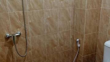A bathroom with a shower, toilet, and tiled floor.