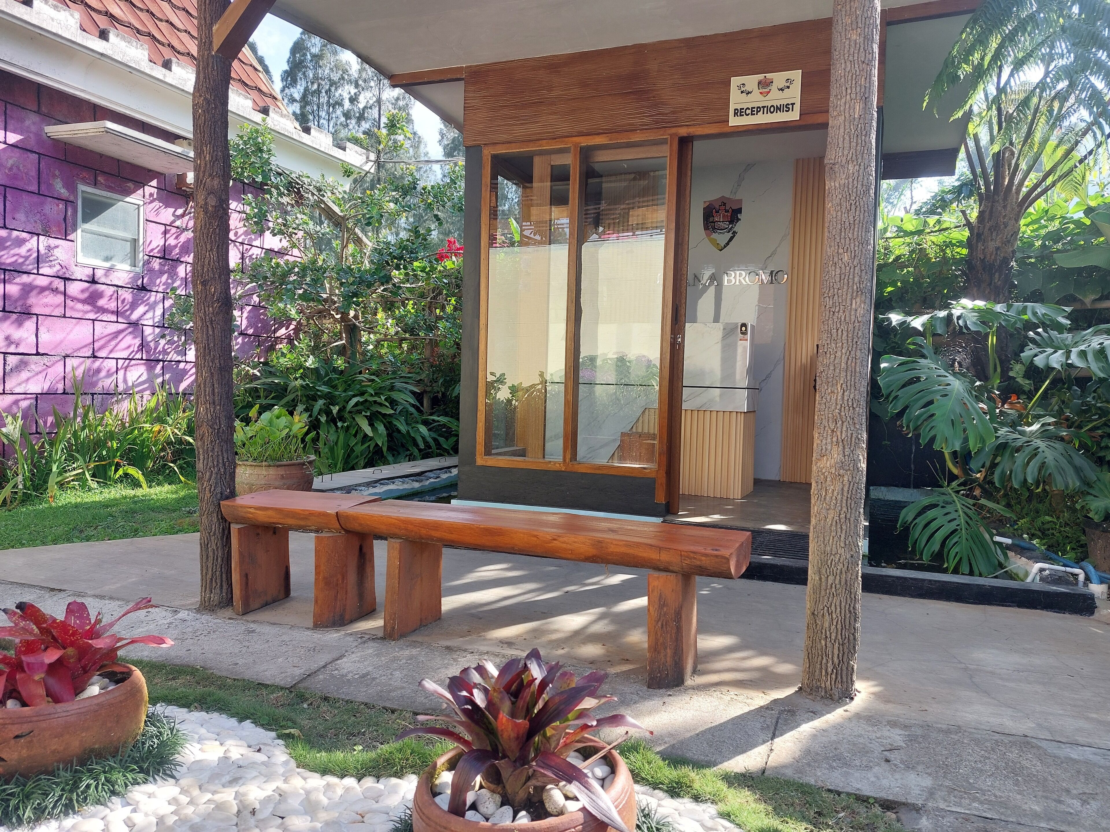 A reception area with a wooden bench, a reception desk, and a sign indicating a receptionist.