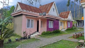 Een rij twee-onder-een-kapwoningen met schotels, een grindpad en een kleine tuin.