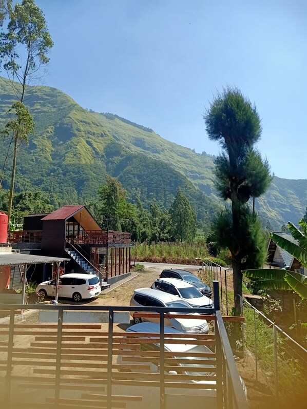 Een parkeerplaats met auto's, een gebouw met een rood dak en een bergachtig landschap op de achtergrond.