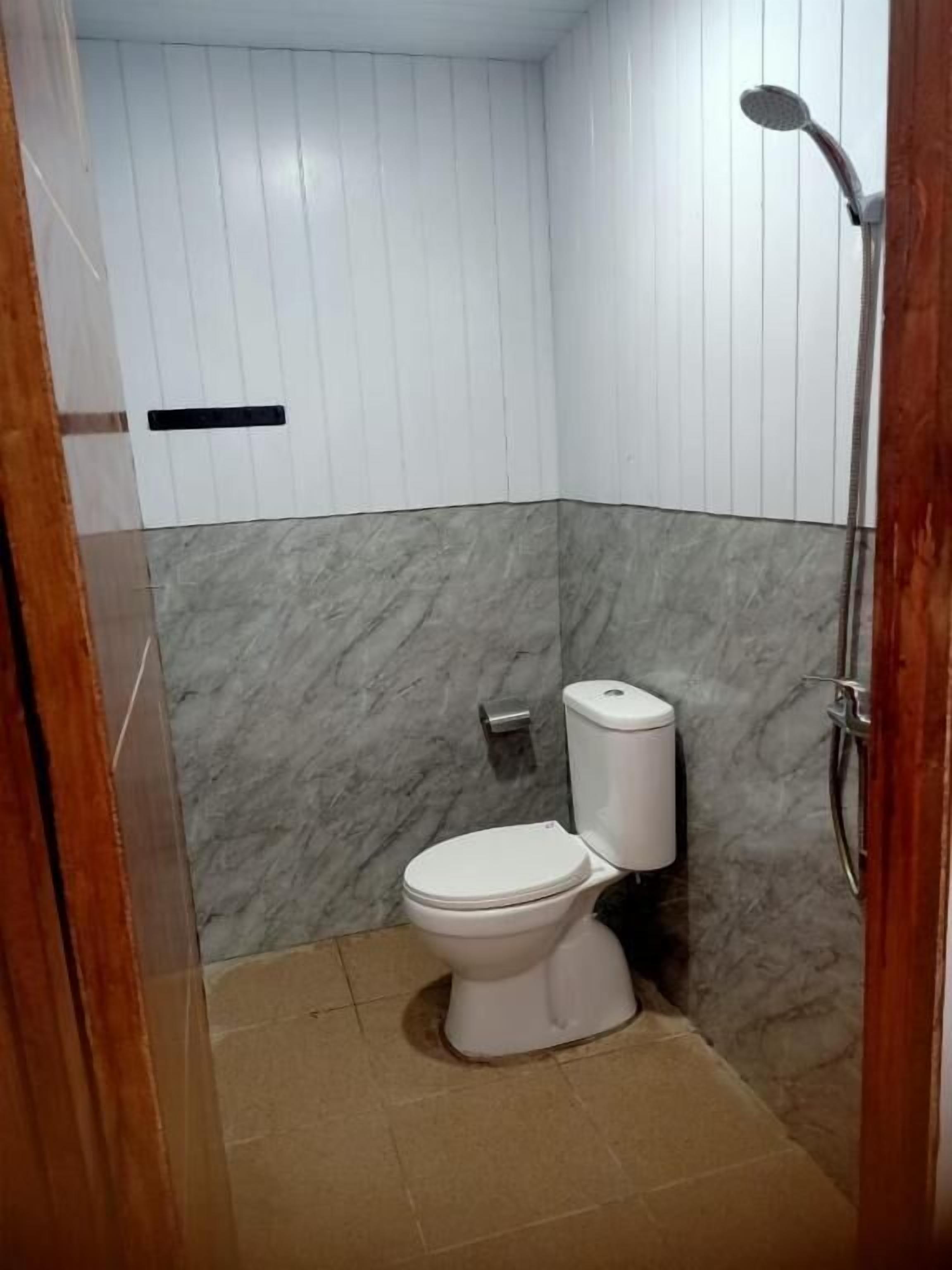 Un baño con inodoro, ducha y pared de mármol.