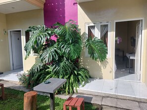 Een binnenplaats met een tafel, stoelen en grote tropische planten.