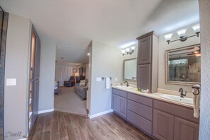 A modern bathroom with dual sinks, a large mirror, and a walk-in shower.