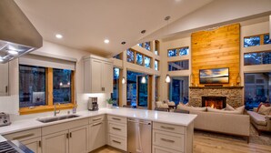 A modern kitchen with a large island, built-in appliances, and a stone fireplace.