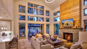A spacious living room with a fireplace, large windows, and a view of the outdoors.