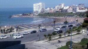 Eine Küstenstadt mit Strand, Hochhäusern und einer Straße mit parkenden Autos.