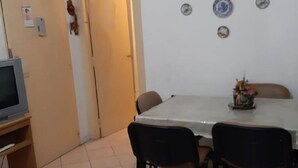 Ein kleiner Essbereich mit Tisch und Stühlen, einem Fernseher auf einem Schrank und einer Wanduhr.