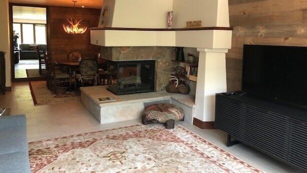 A modern living room with a stone fireplace, a flat-screen TV, and a dining area with a table and chairs. - Luxurious 1br+loft - Ski-in/ski-out Access To Beaver Creek 1 Bedroom Condo by RedAwning (Avon)