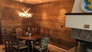 A dining area with a wooden wall, a chandelier, a round table, and chairs. - Luxurious 1br+loft - Ski-in/ski-out Access To Beaver Creek 1 Bedroom Condo by RedAwning (Avon)