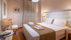 Et hotelværelse med seng, sengebord, lampe og et vindue med gardiner.