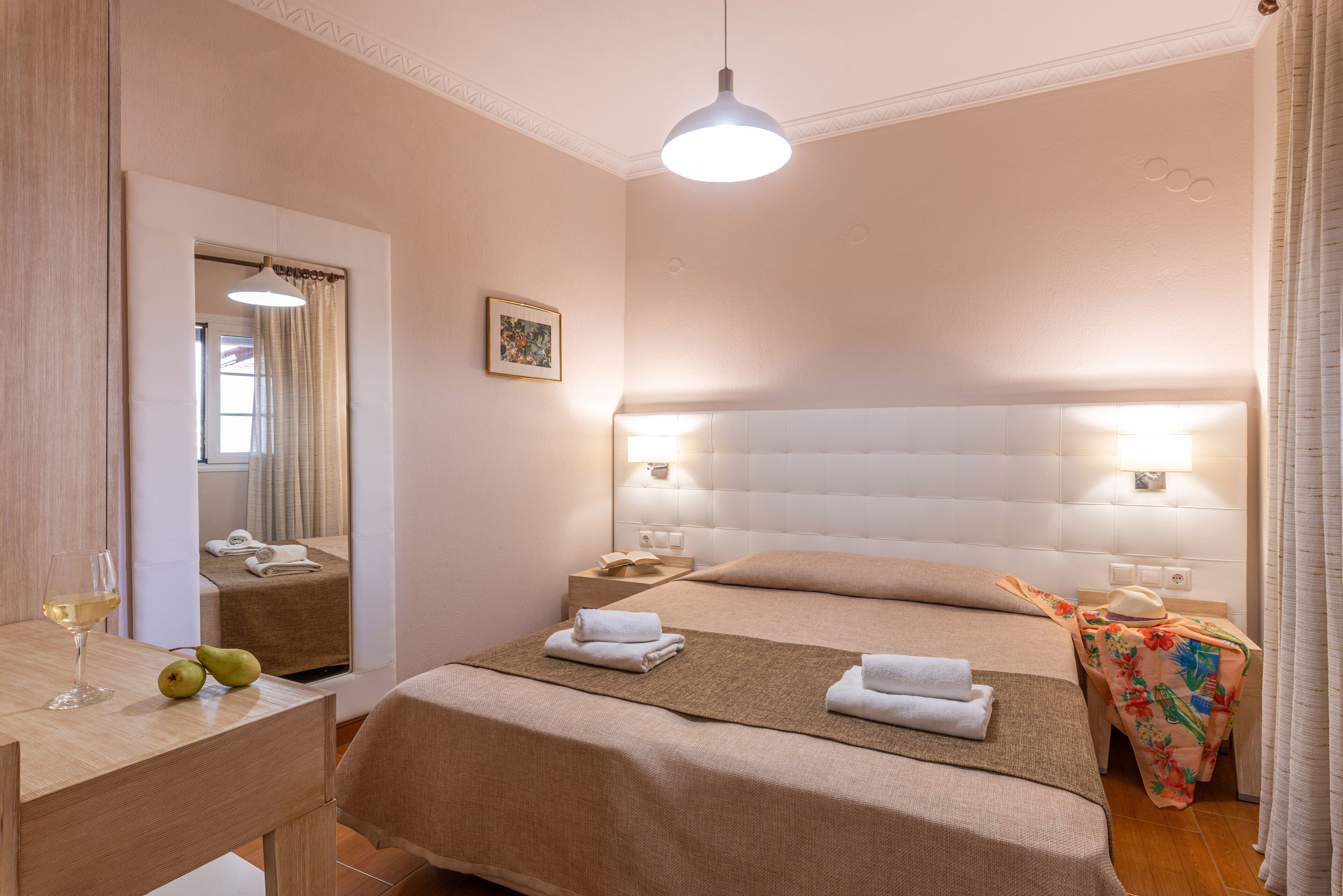 Ein Hotelzimmer mit einem großen Bett, einem Nachttisch mit Lampe, einem Spiegel und Blick ins Bad.