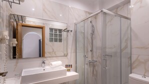 Et moderne badeværelse med en marmorvask, en brusekabine med glasvægge og et toilet.