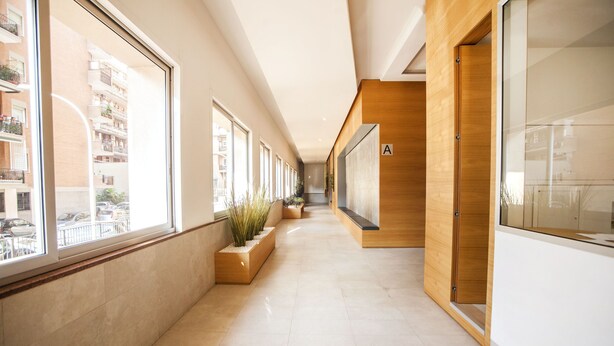 A modern hotel corridor with large windows, wooden paneling, and a tiled floor. - Appia Near Underground Station (Roma)