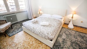 A hotel room with a bed, two bedside lamps, a chair, a window, and a radiator. - Appia Near Underground Station (Roma)
