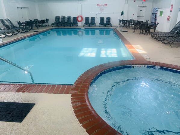 An indoor swimming pool with a clear water surface, a brick edge, and a lifebuoy on the wall.