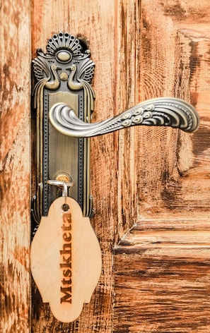 A door with a metal handle and a wooden key tag with the name "Mitskhetra" on it. - Palm Hotel (Batumi)
