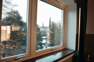 Una ventana con vistas a la aguja de una iglesia y árboles.