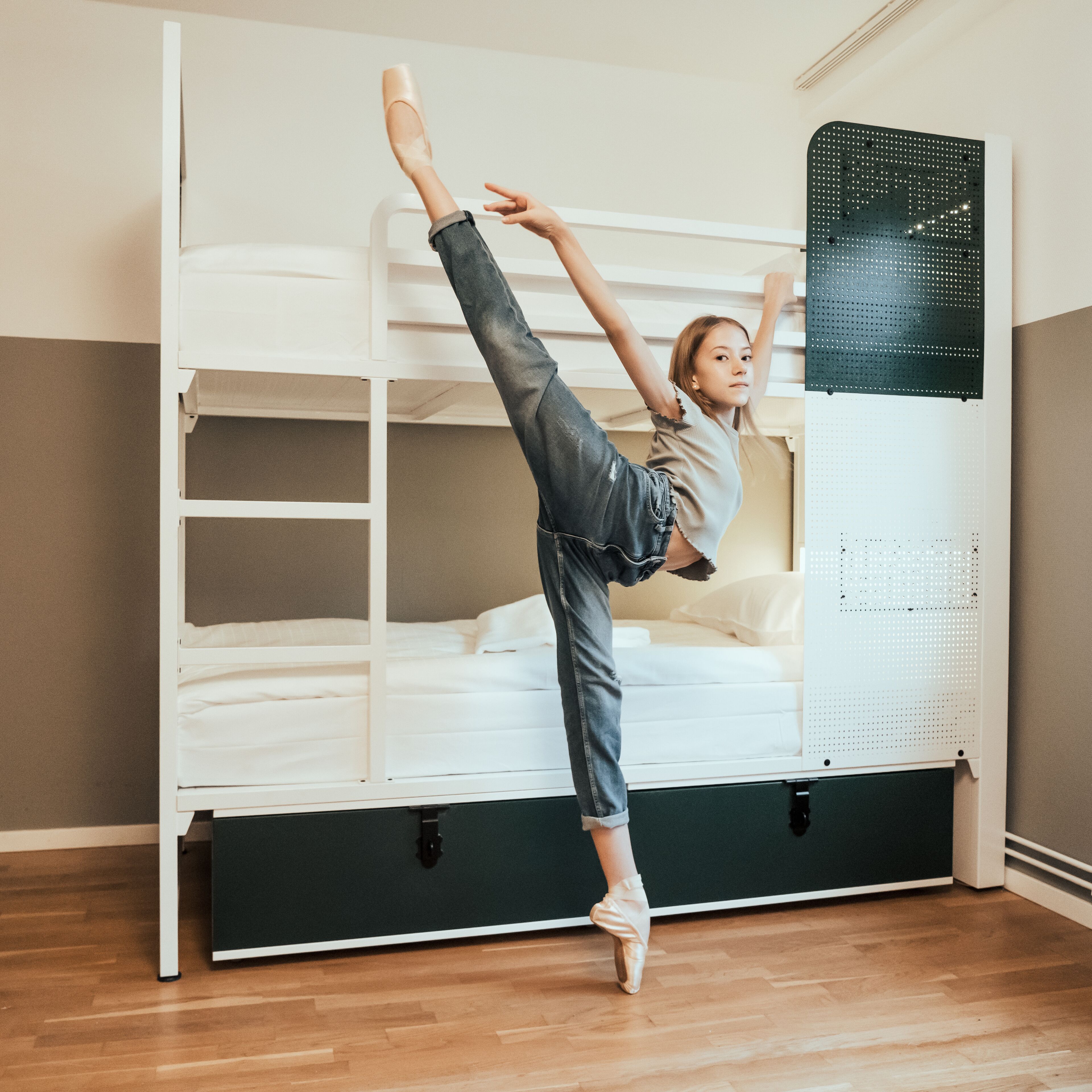 Une chambre avec un lit superposé, un meuble de rangement noir et un plancher en bois.