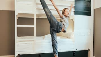 Une chambre avec un lit superposé, un meuble de rangement noir et un plancher en bois.