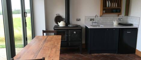 A kitchen with a wooden table, a stove, a sink, and a cabinet.