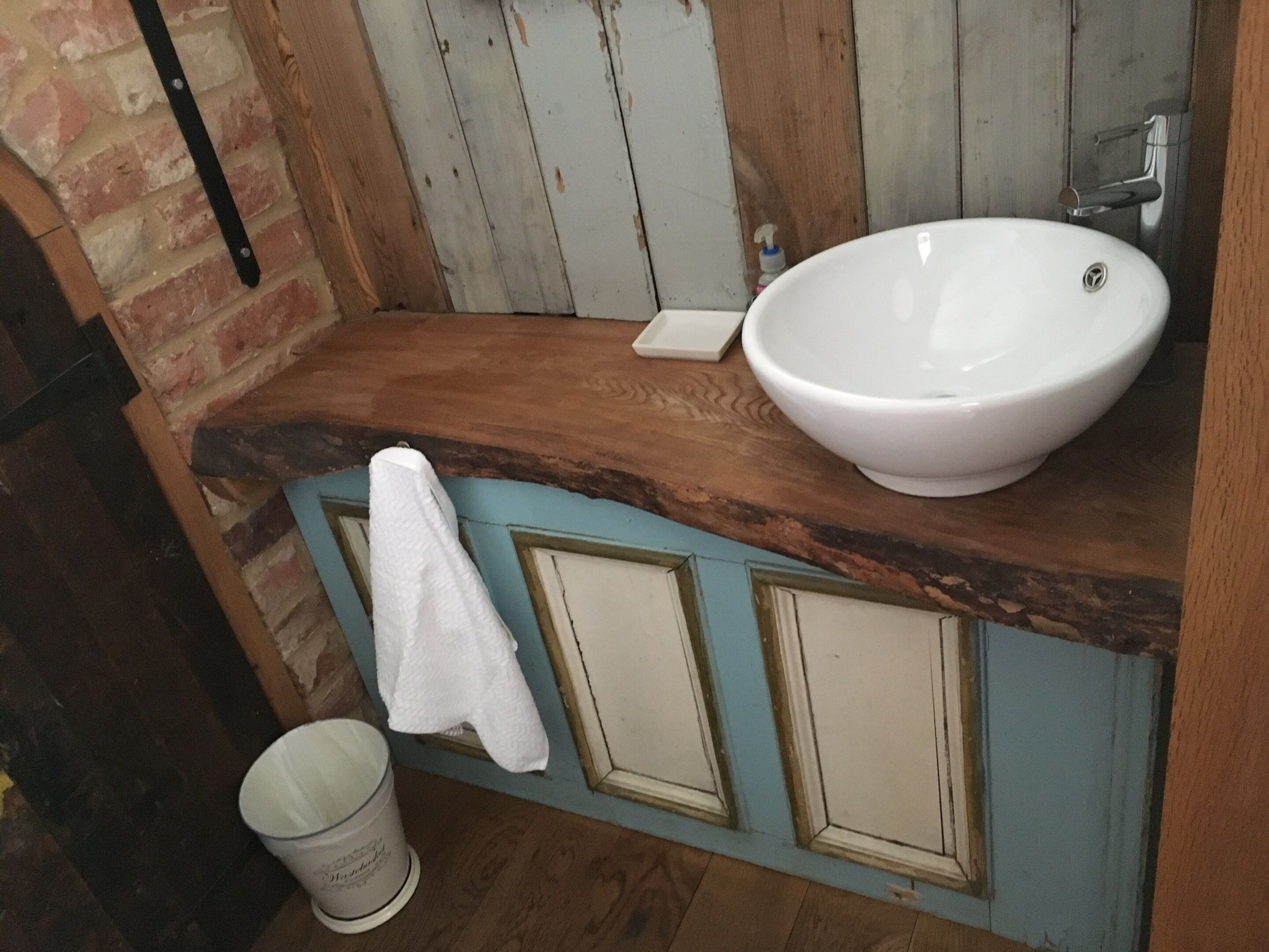 A bathroom with a wooden countertop, a white sink, and a towel hanging on the wall.