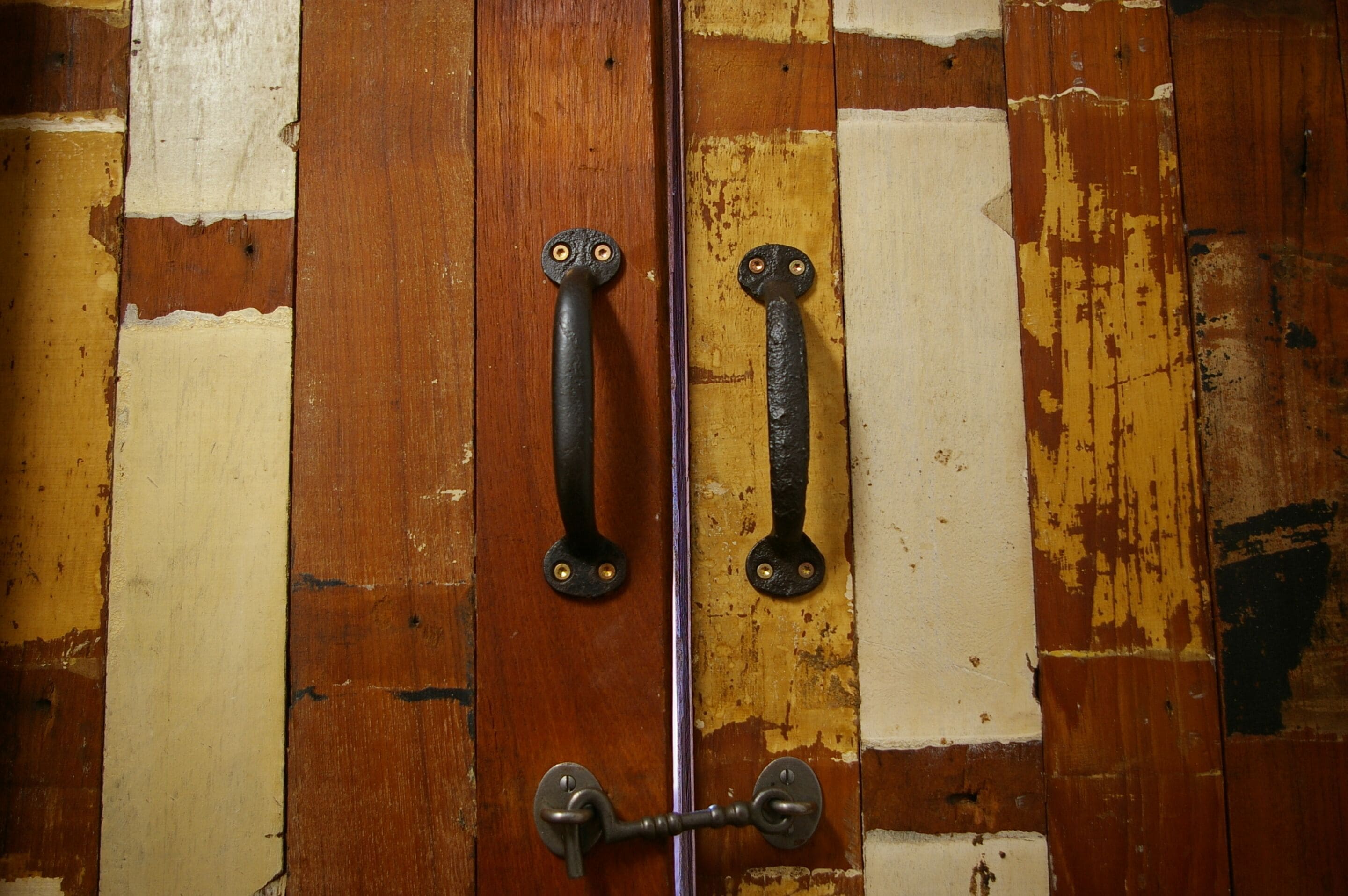Une porte en bois, dotée de deux poignées métalliques et d’un trou de serrure.