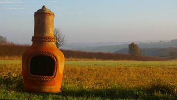 A rustic, weathered bottle-shaped object placed on a railway track in a rural landscape with rolling hills and sparse trees in the background.