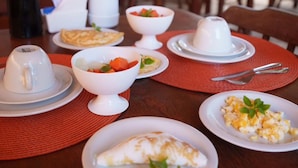 A dining table set with breakfast items including eggs, toast, and fruit.
