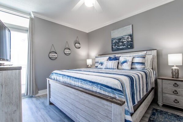 Een slaapkamer met een groot bed, een nachtkastje, een dressoir en een raam met gordijnen.