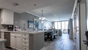 Een moderne keuken met witte kasten, een groot eiland en een zithoek met een bank.