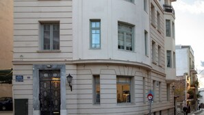 A multi-story building with a curved balcony, large windows, and a prominent entrance with a decorative door. - Neoclassical Apartment near Syntagma - Plaka by GHH (Athens)