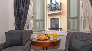 A cozy room with a round table set for breakfast, featuring fruits and drinks. - Neoclassical Apartment near Syntagma - Plaka by GHH (Athens)