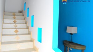 Un escalier orné d’un motif géométrique, un mur bleu et une lampe posée sur une table en bois.