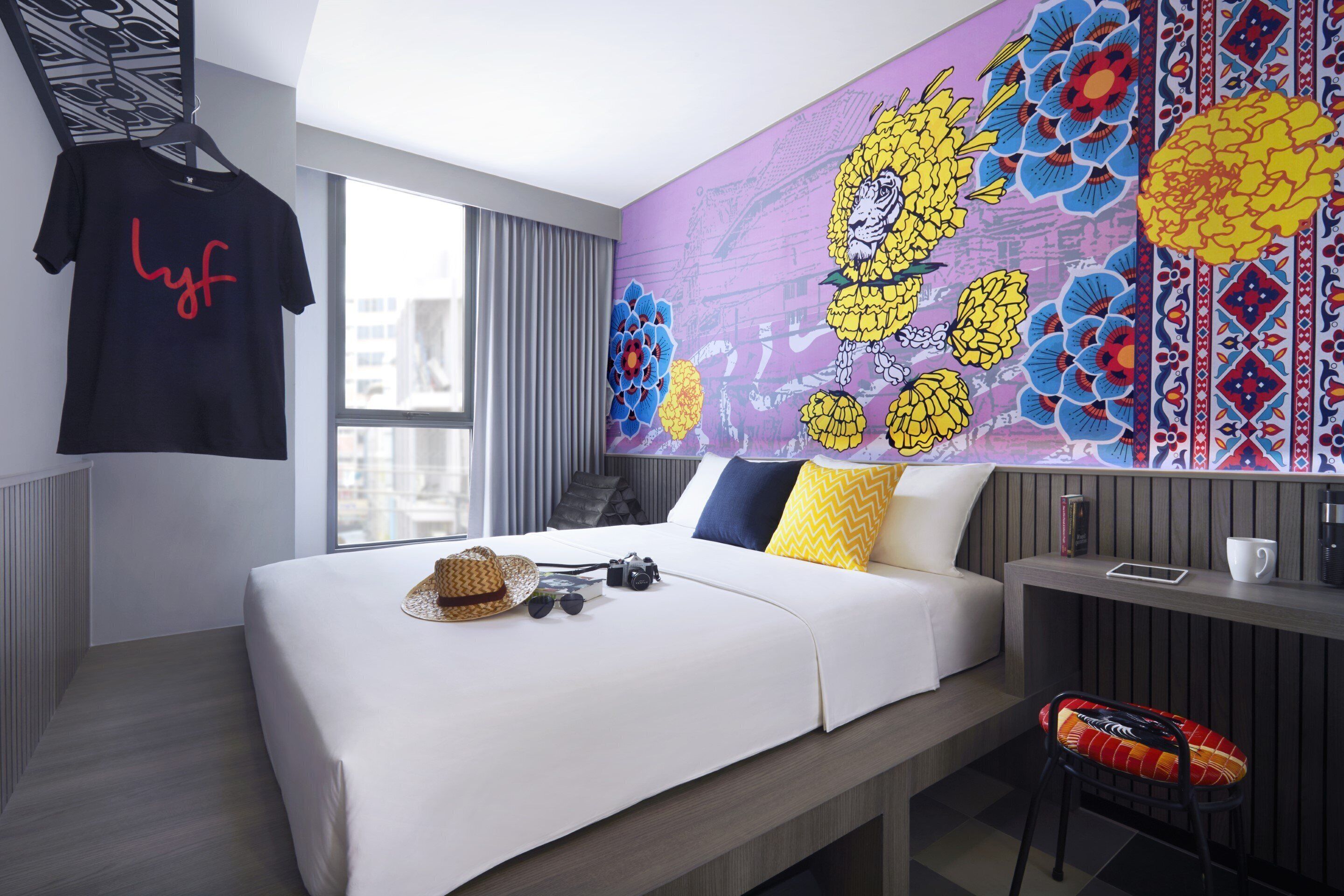 Ein modernes Hotelzimmer mit einem großen Bett, einem Schreibtisch und einer lebhaften Blumenmalerei an der Wand.