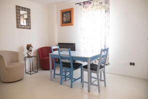 A dining area with a table and chairs, a sofa, a small side table, and a mirror on the wall.