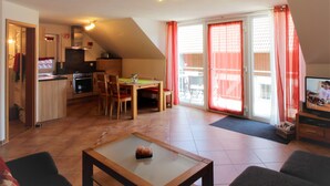Un espacio habitable compacto con cocina, comedor y un televisor pequeño.
