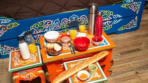 A colorful table set with various breakfast items including bread, a bottle of milk, and a thermos.