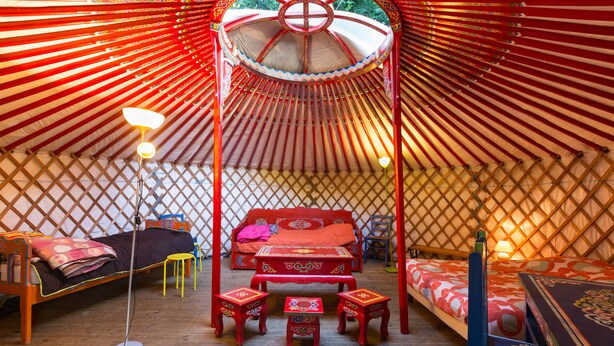 A traditional yurt with a bed, a small table, and a chair.